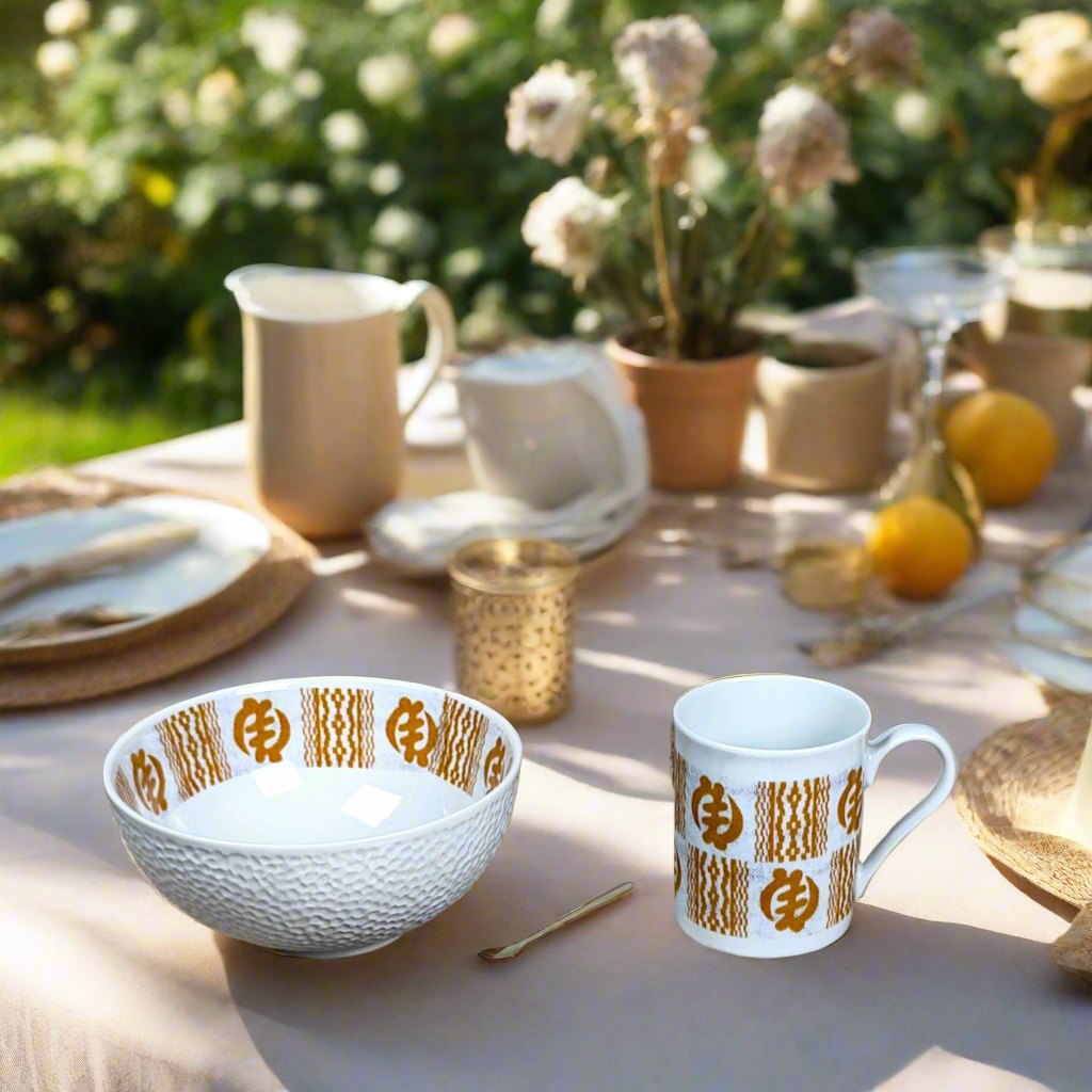 Coffret petit déjeuner en porcelaine fine française, orné d’un motif Ethnique "Adinkra" de Côte d'Ivoire, composé d'une petite assiette, d'un bol et d'un MUG, présentés dans une boîte prestige.