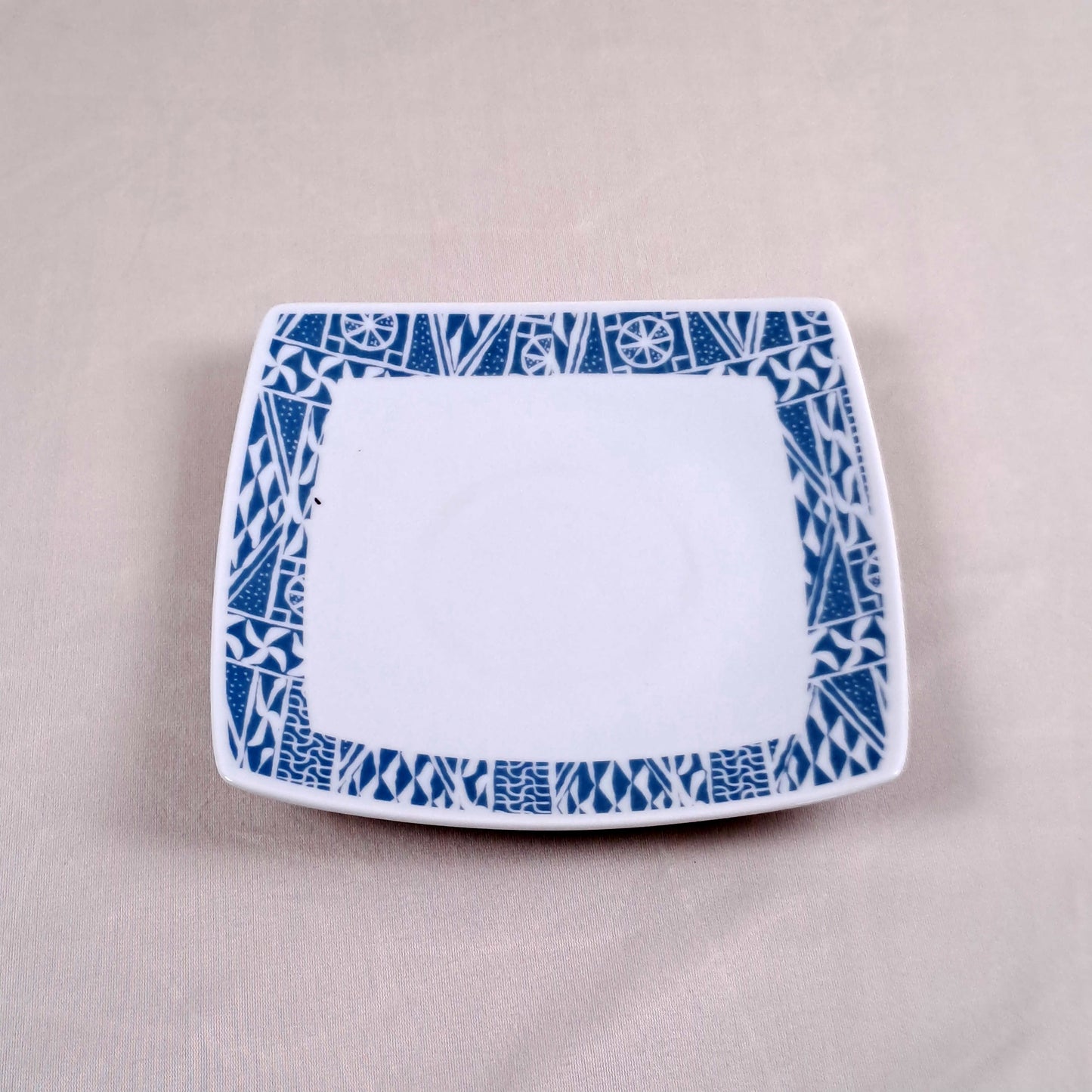 Coffret d'assiettes carrées en porcelaine fine Française fabriquées à la demande avec motif anneau ethnique d'Afrique "Ndop", du Cameroun présenté dans un coffret de 6 assiettes.