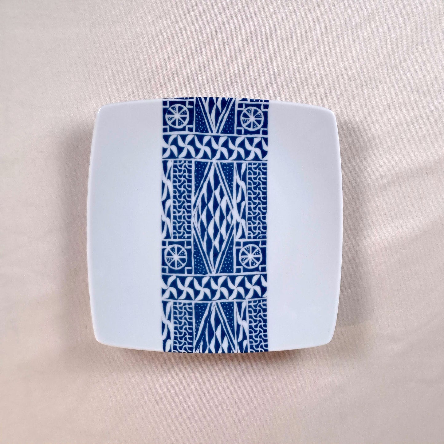 Coffret d'assiettes carrées en porcelaine fine Française fabriquées à la demande avec motif bande ethnique d'Afrique "Ndop" bleu du Cameroun, présenté dans un coffret de 6 assiettes.