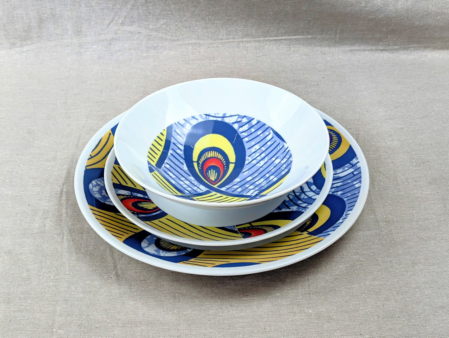 Coffret d'assiettes rondes en porcelaine fine Française fabriquées à la demande avec motif anneaux larges WAX d'afrique "Nos destins entrelacés" dans coffret de 6 assiettes.