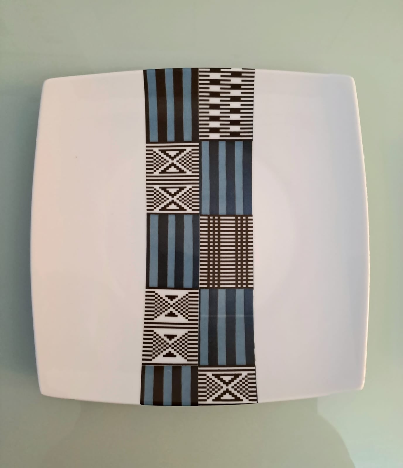 Coffret d'assiettes carrées en porcelaine fine Française fabriquées à la demande avec motif bande ethnique "Kounta" ou "Kanta" bleu du Niger, présenté dans un coffret de 6 assiettes