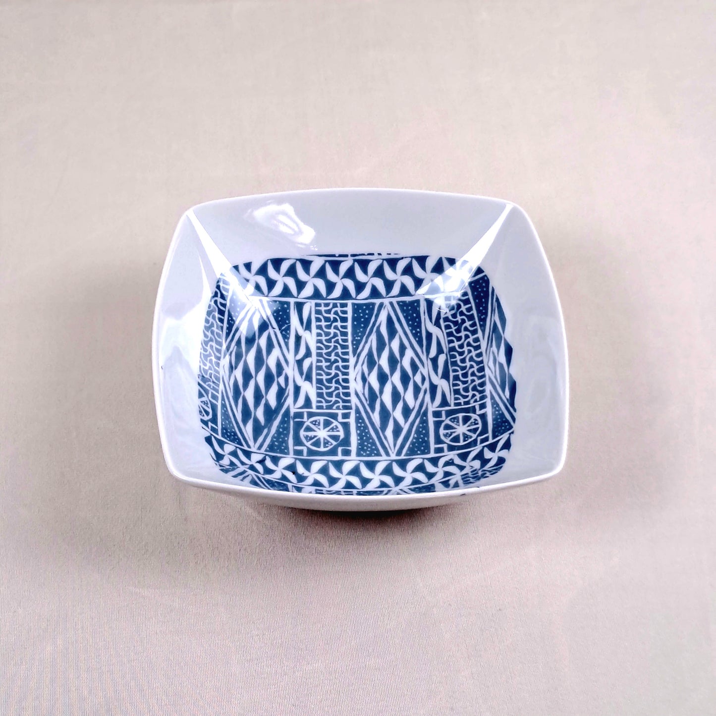 Coffret d'assiettes carrées en porcelaine fine Française fabriquées à la demande avec motif anneau ethnique d'Afrique "Ndop", du Cameroun présenté dans un coffret de 6 assiettes.