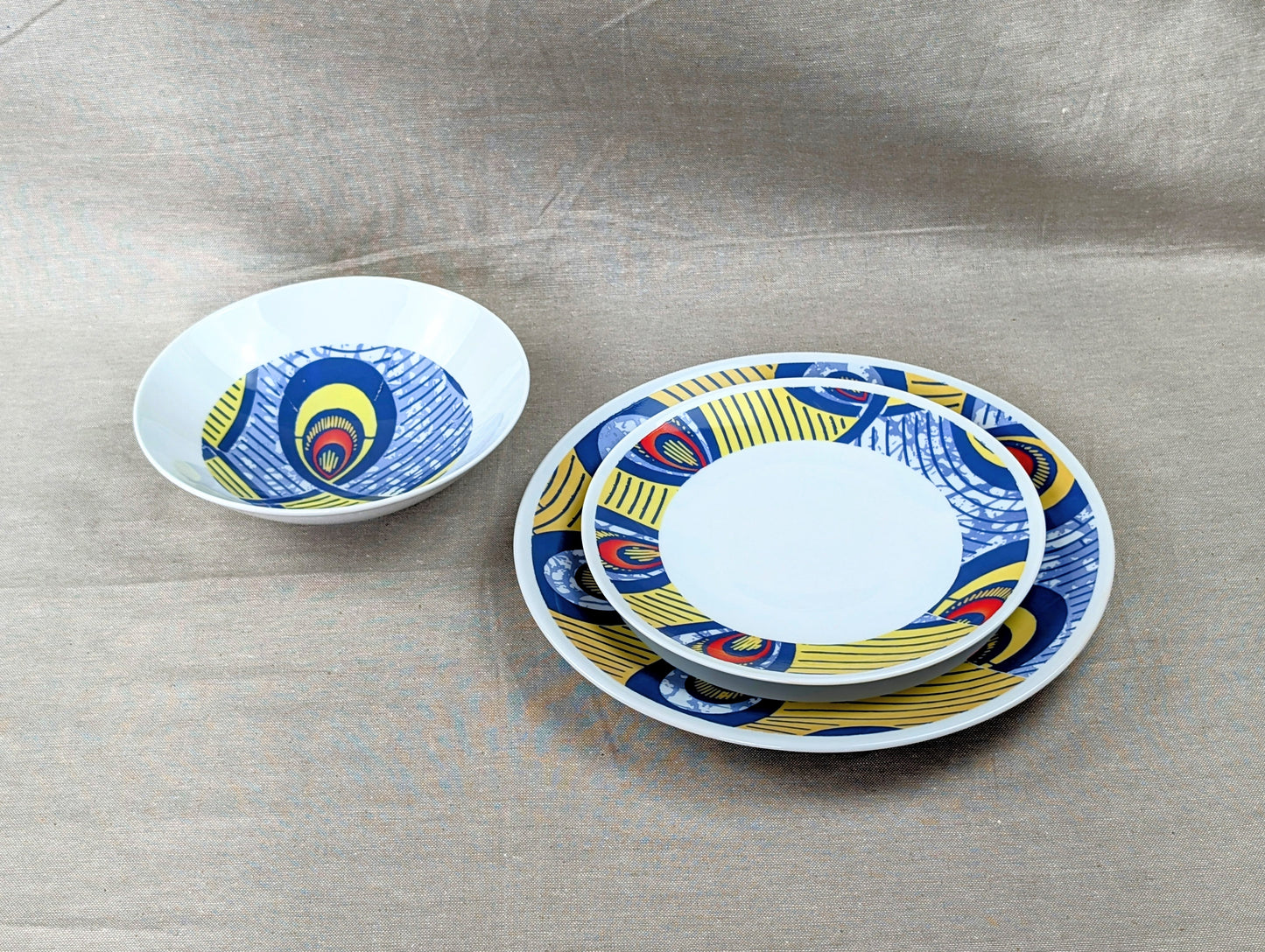 Coffret d'assiettes rondes en porcelaine fine Française fabriquées à la demande avec motif anneaux larges WAX d'afrique "Nos destins entrelacés" dans coffret de 6 assiettes.