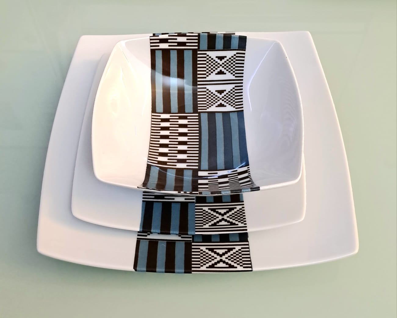 Coffret d'assiettes carrées en porcelaine fine Française fabriquées à la demande avec motif bande ethnique "Kounta" ou "Kanta" bleu du Niger, présenté dans un coffret de 6 assiettes