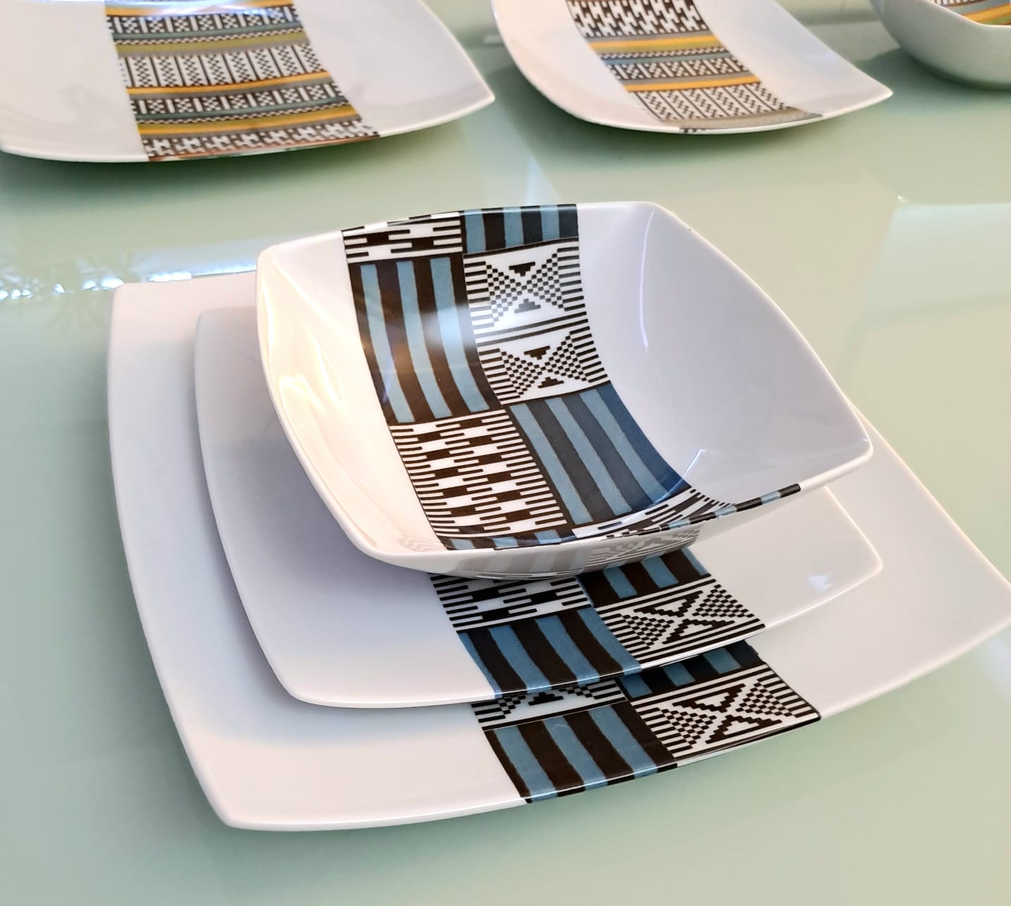 Coffret d'assiettes carrées en porcelaine fine Française fabriquées à la demande avec motif bande ethnique "Kounta" ou "Kanta" bleu du Niger, présenté dans un coffret de 6 assiettes
