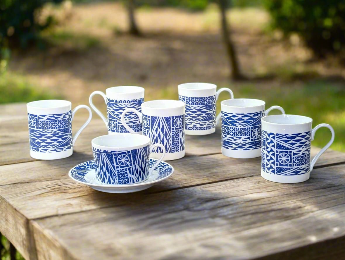 Mugs et tasse Ndop bleu indigo et blanc alignés sur une table en bois patiné au jardin