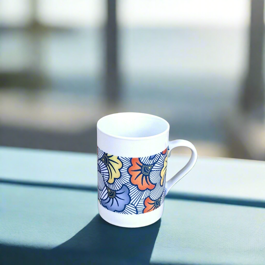 Coffret petit déjeuner en porcelaine fine française, orné d’un motif WAX "Fleurs de Mariage" bleu, composé d'une petite assiette, d'un bol et d'un MUG, présentés dans une boîte prestige.