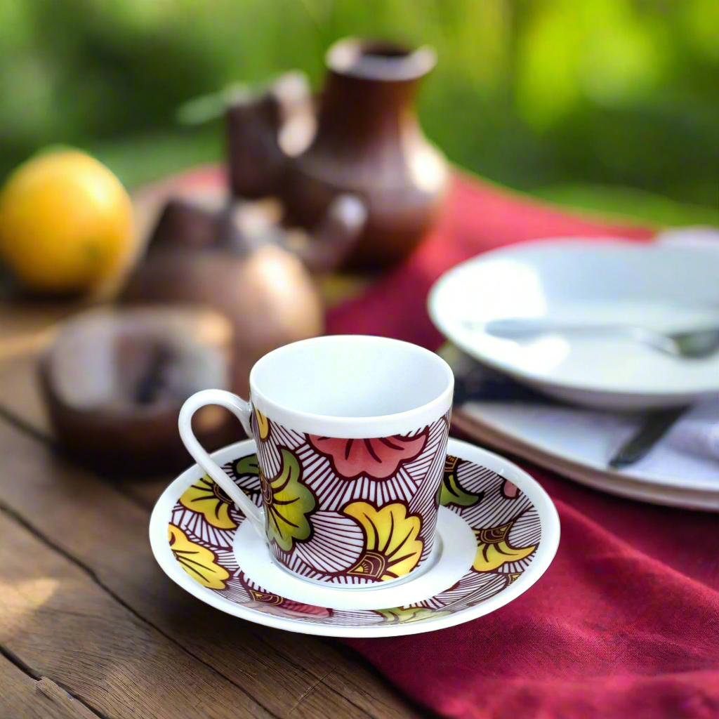 Vue de trois quarts : tasse à café Fleurs de Mariage rouge magenta sur soucoupe, serviette bordeaux et cruche brune