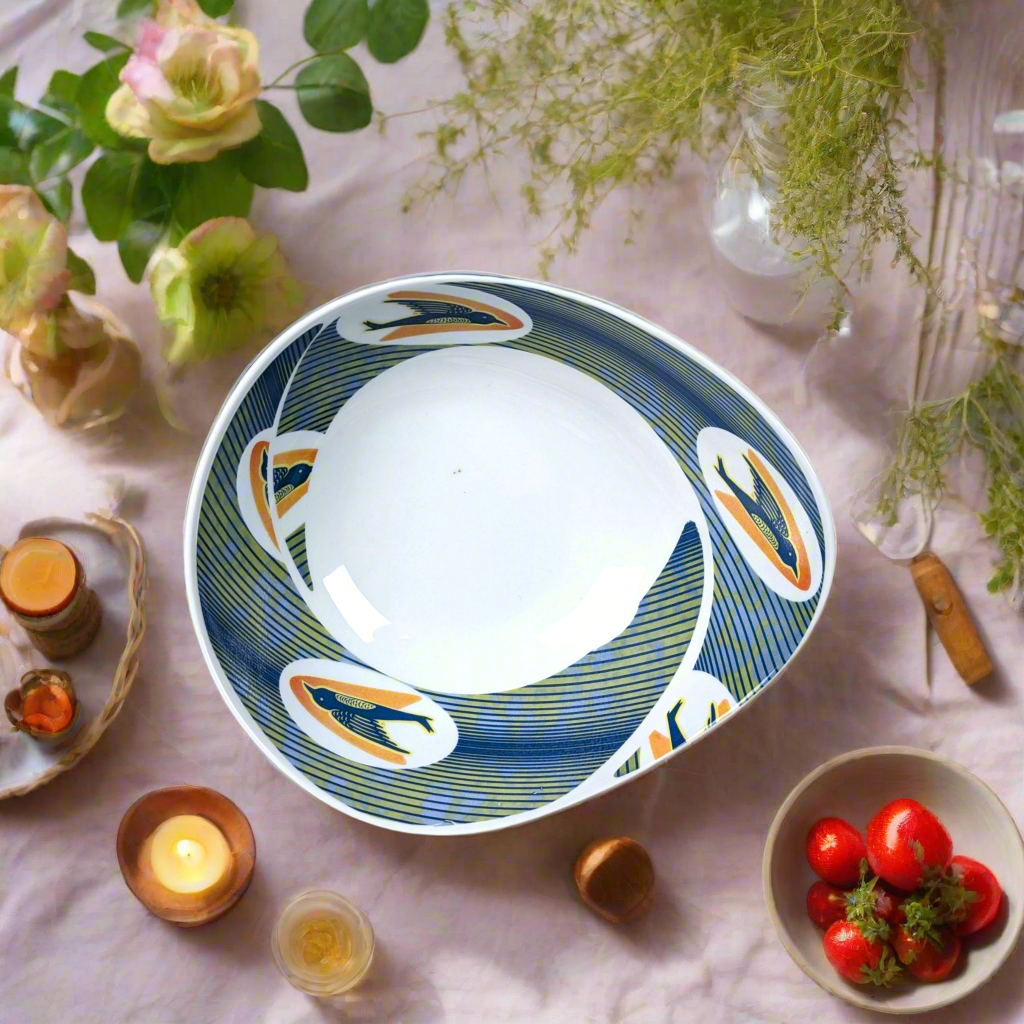 Vue zénithale : saladier ovale Ntaban Hirondelles sur nappe rose pâle, bougies, tomates cerises et herbes fines