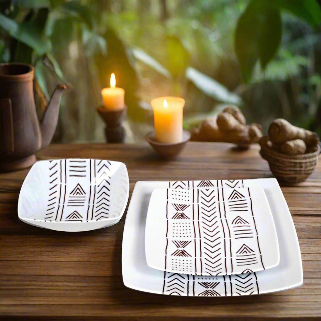 Plongée de trois quarts : bol et assiettes carrées Bogolan brun sur table en bois, théière, bougies et paniers