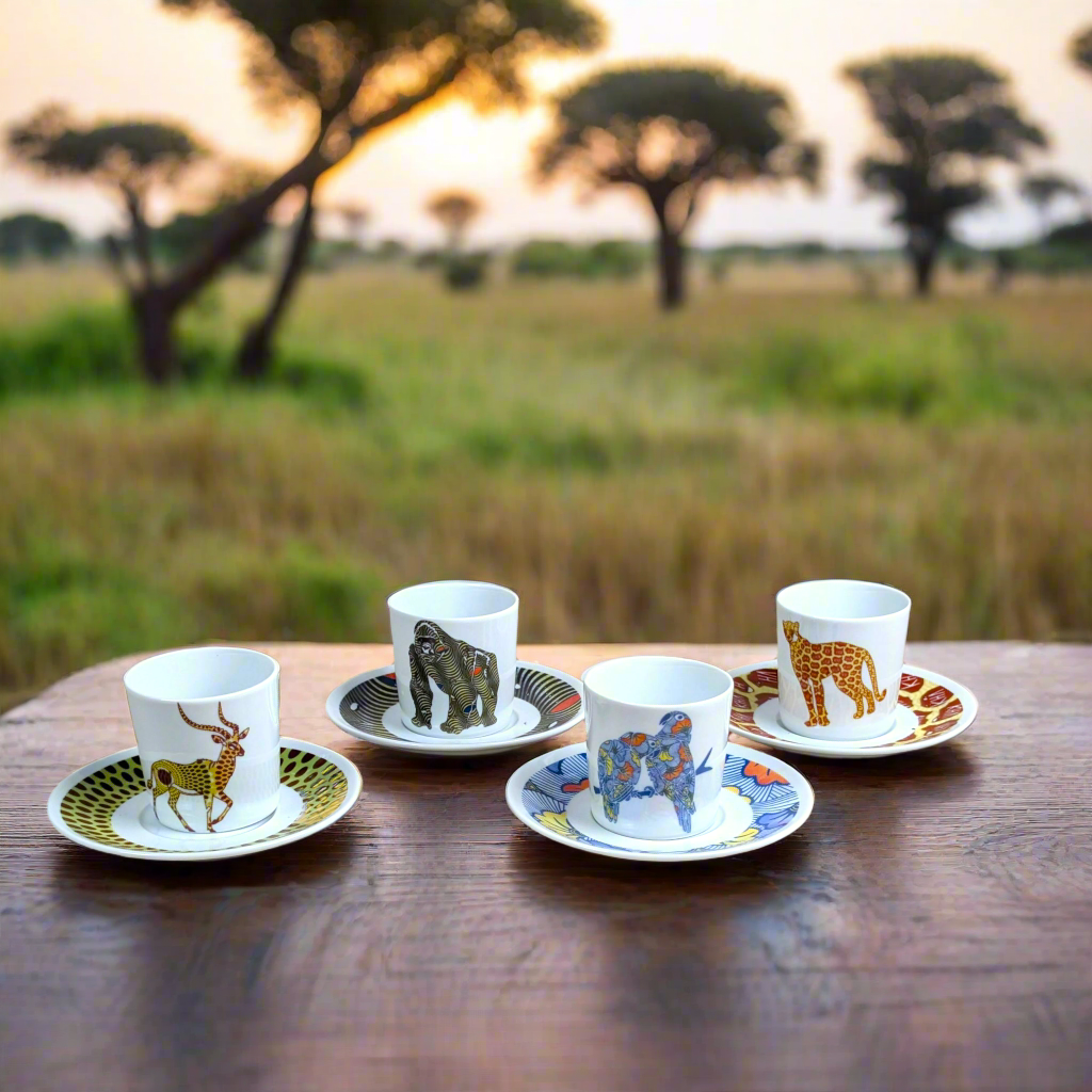 Plan large au coucher du soleil : quatre tasses Silhouettes wax sur soucoupes, savane et acacias en fond