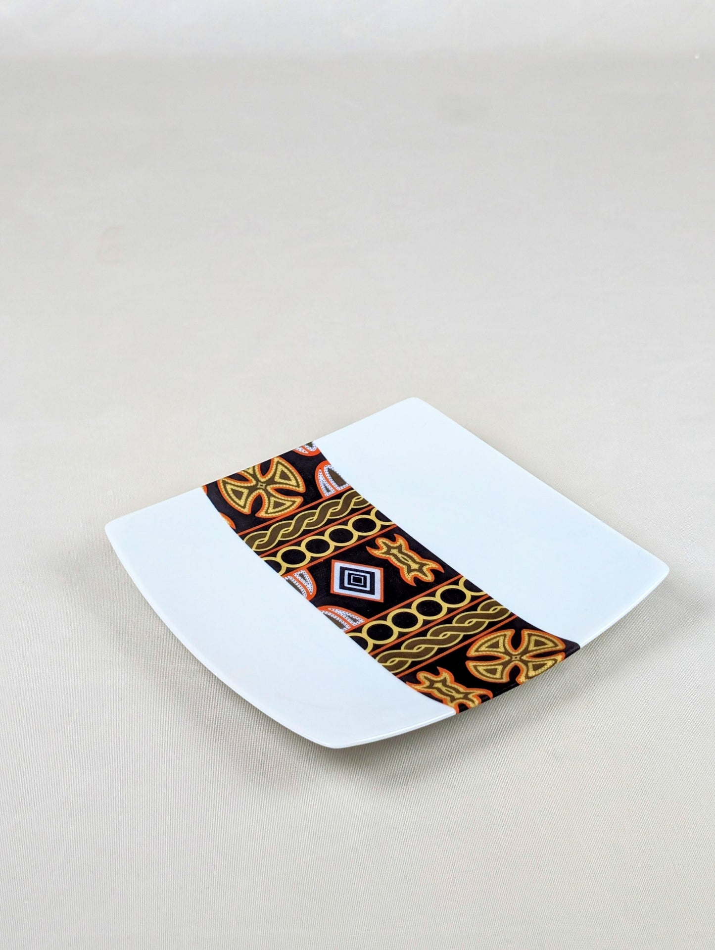 Coffret d'assiettes carrées en porcelaine fine Française fabriquées à la demande avec motif bande ethnique d'Afrique "Ndop" noir du Cameroun, présenté dans un coffret de 6 assiettes.