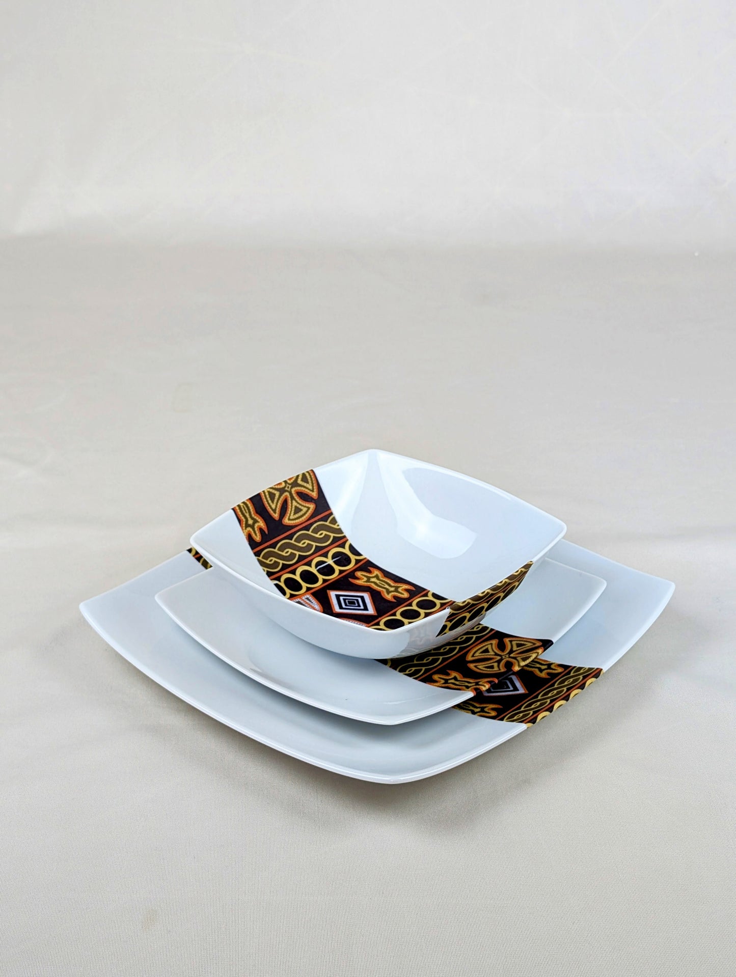 Coffret d'assiettes carrées en porcelaine fine Française fabriquées à la demande avec motif bande ethnique d'Afrique "Ndop" noir du Cameroun, présenté dans un coffret de 6 assiettes.