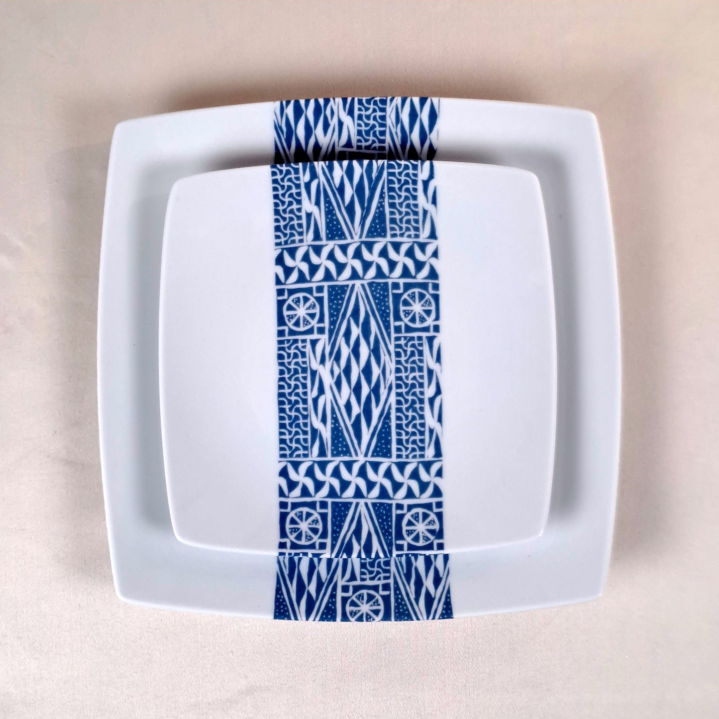 Coffret d'assiettes carrées en porcelaine fine Française fabriquées à la demande avec motif bande ethnique d'Afrique "Ndop" bleu du Cameroun, présenté dans un coffret de 6 assiettes.