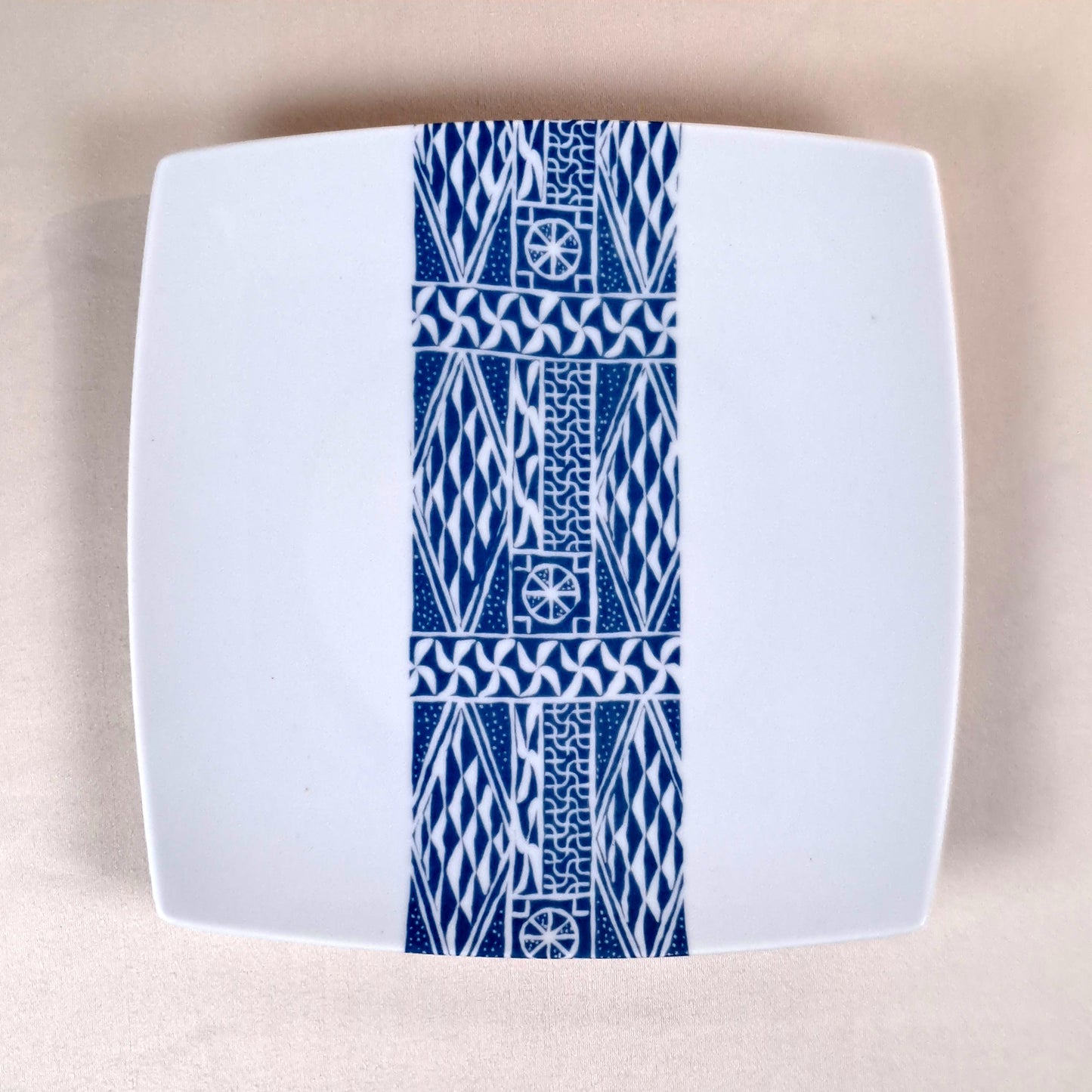 Coffret d'assiettes carrées en porcelaine fine Française fabriquées à la demande avec motif bande ethnique d'Afrique "Ndop" bleu du Cameroun, présenté dans un coffret de 6 assiettes.