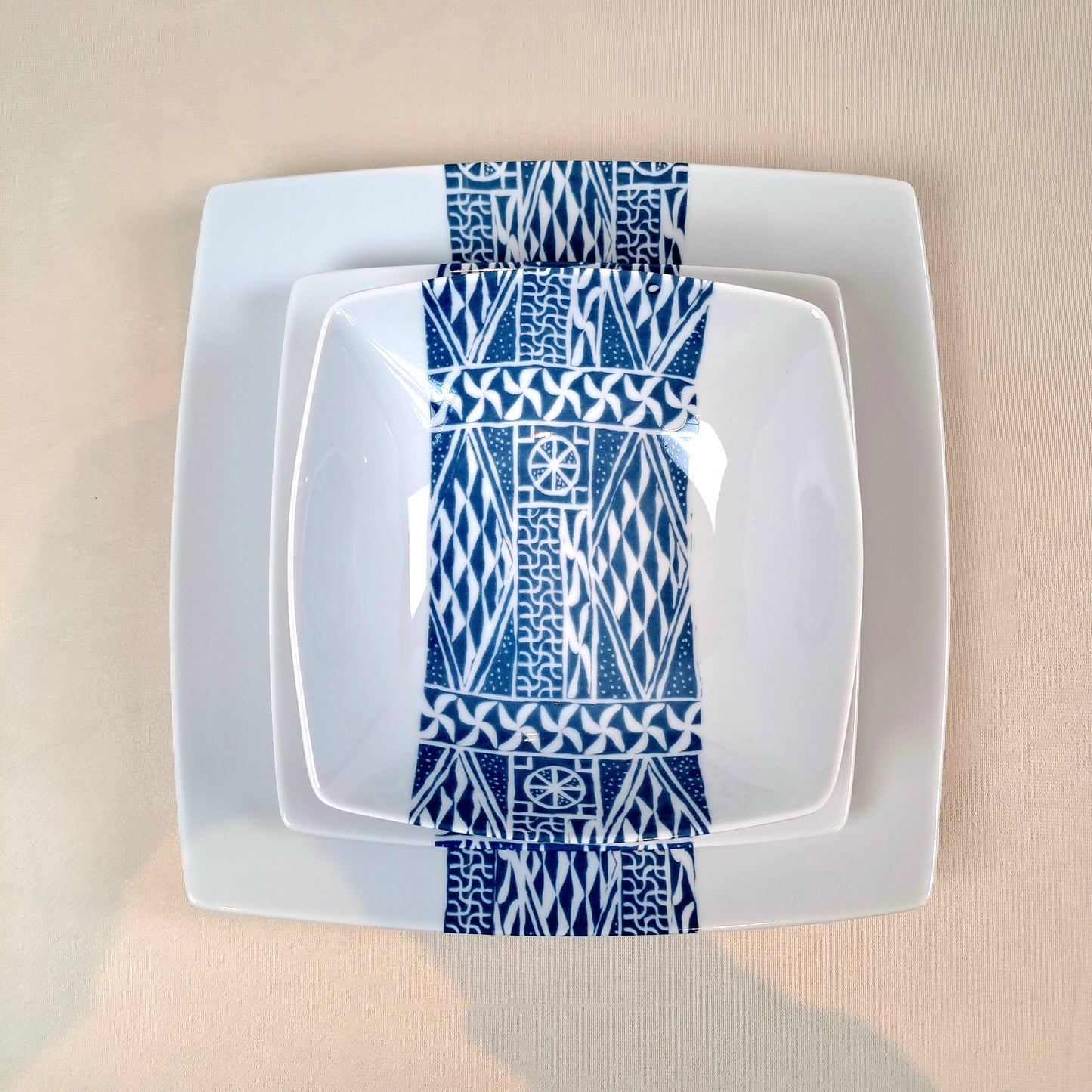 Coffret d'assiettes carrées en porcelaine fine Française fabriquées à la demande avec motif bande ethnique d'Afrique "Ndop" bleu du Cameroun, présenté dans un coffret de 6 assiettes.