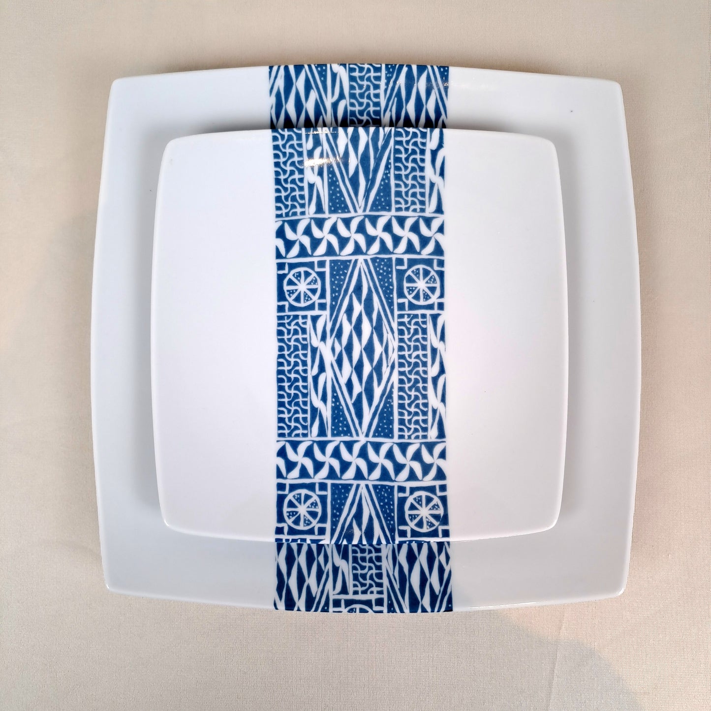 Coffret d'assiettes carrées en porcelaine fine Française fabriquées à la demande avec motif bande ethnique d'Afrique "Ndop" bleu du Cameroun, présenté dans un coffret de 6 assiettes.