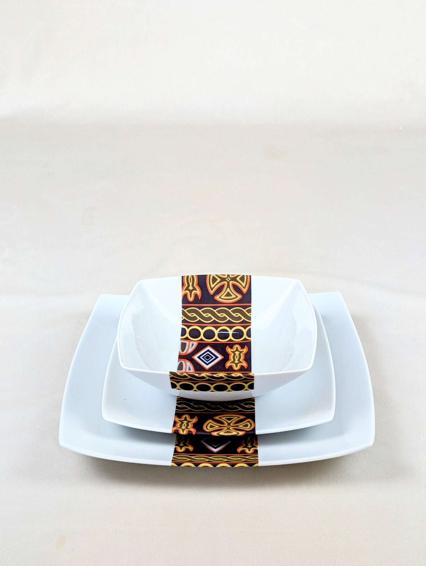 Coffret d'assiettes carrées en porcelaine fine Française fabriquées à la demande avec motif bande ethnique d'Afrique "Ndop" noir du Cameroun, présenté dans un coffret de 6 assiettes.
