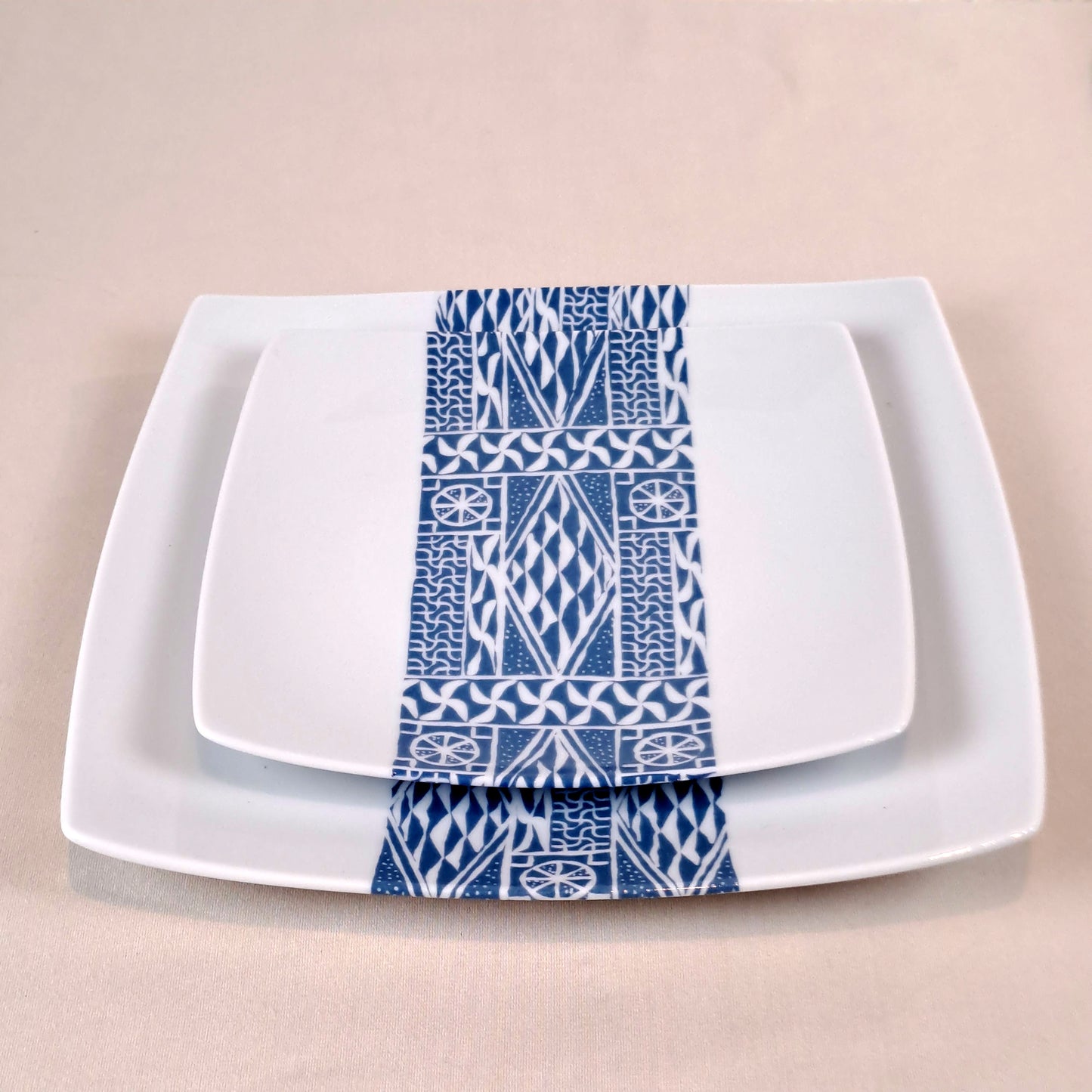 Coffret d'assiettes carrées en porcelaine fine Française fabriquées à la demande avec motif bande ethnique d'Afrique "Ndop" bleu du Cameroun, présenté dans un coffret de 6 assiettes.