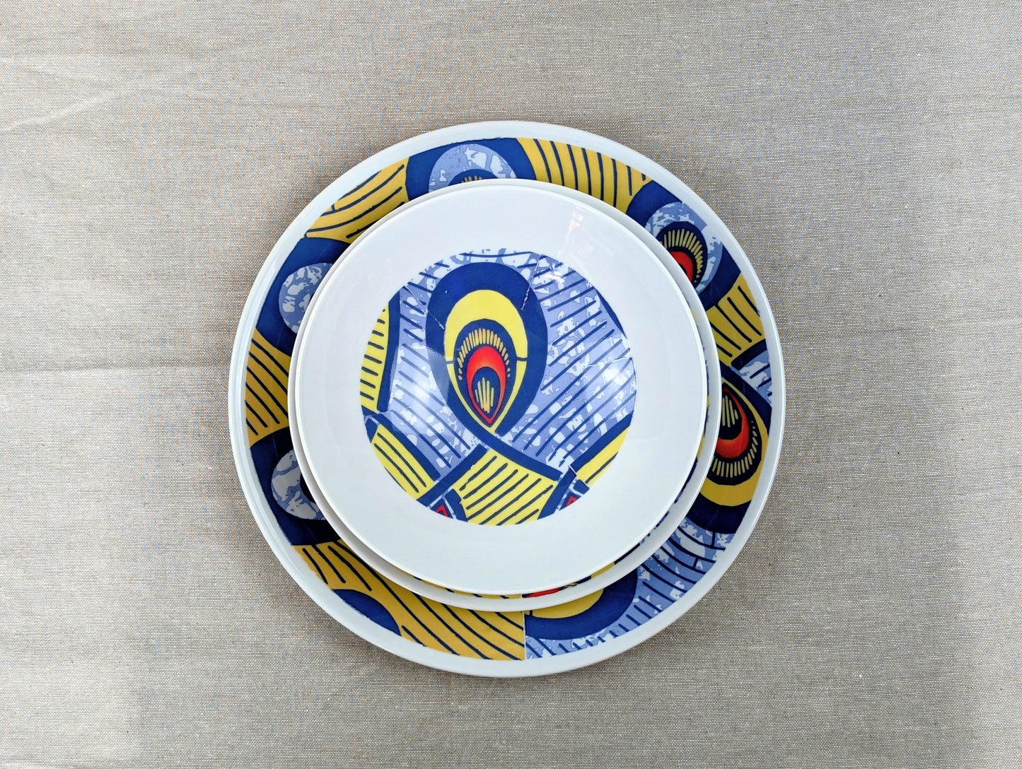 Coffret d'assiettes rondes en porcelaine fine Française fabriquées à la demande avec motif anneaux larges WAX d'afrique "Nos destins entrelacés" dans coffret de 6 assiettes.