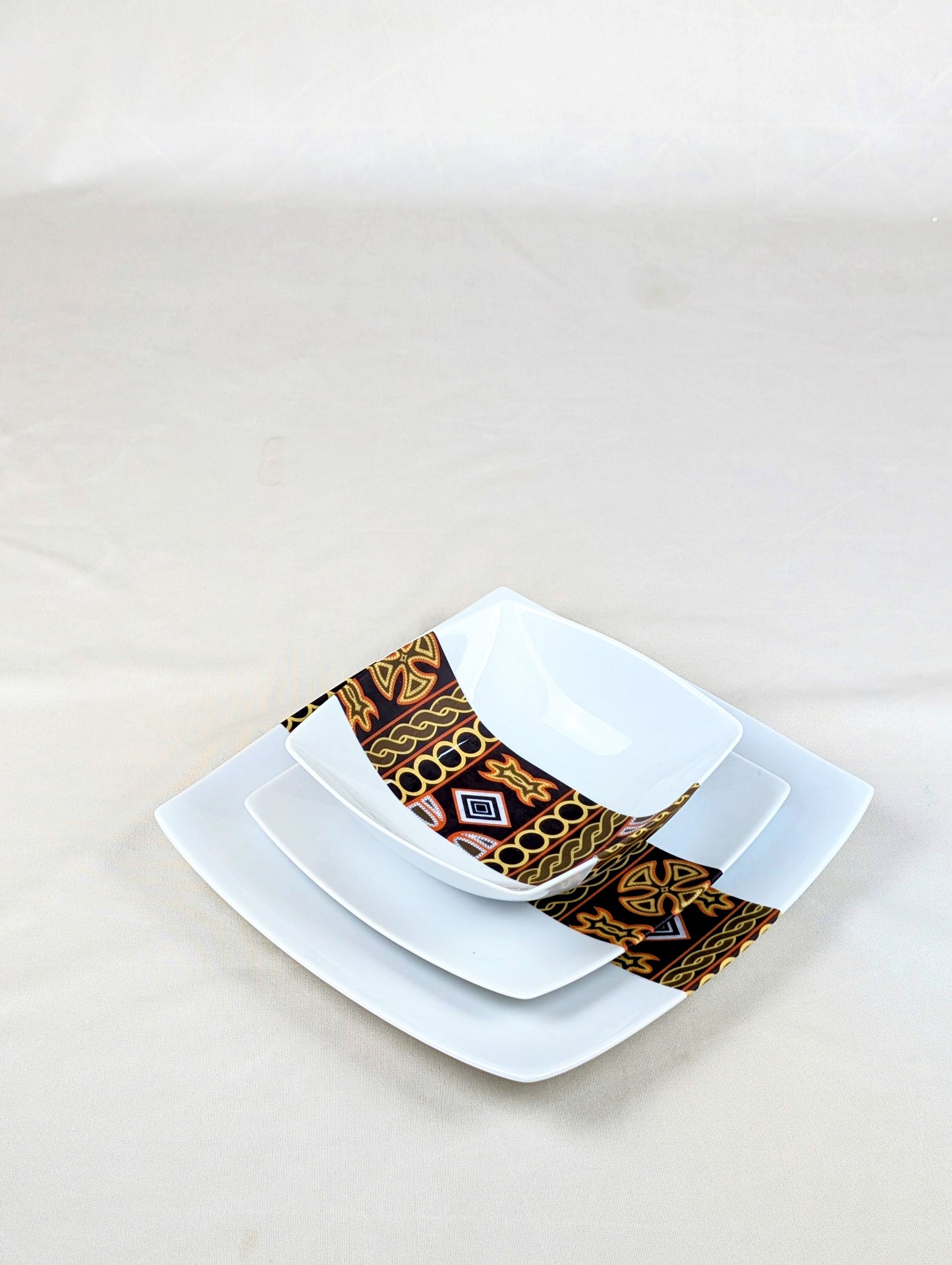 Coffret d'assiettes carrées en porcelaine fine Française fabriquées à la demande avec motif bande ethnique d'Afrique "Ndop" noir du Cameroun, présenté dans un coffret de 6 assiettes.