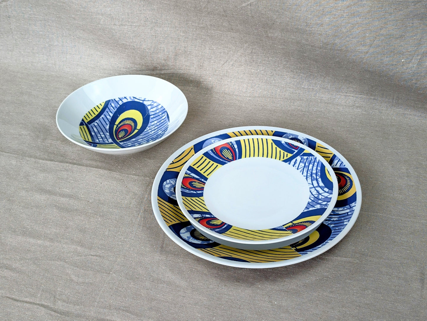 Coffret d'assiettes rondes en porcelaine fine Française fabriquées à la demande avec motif anneaux larges WAX d'afrique "Nos destins entrelacés" dans coffret de 6 assiettes.