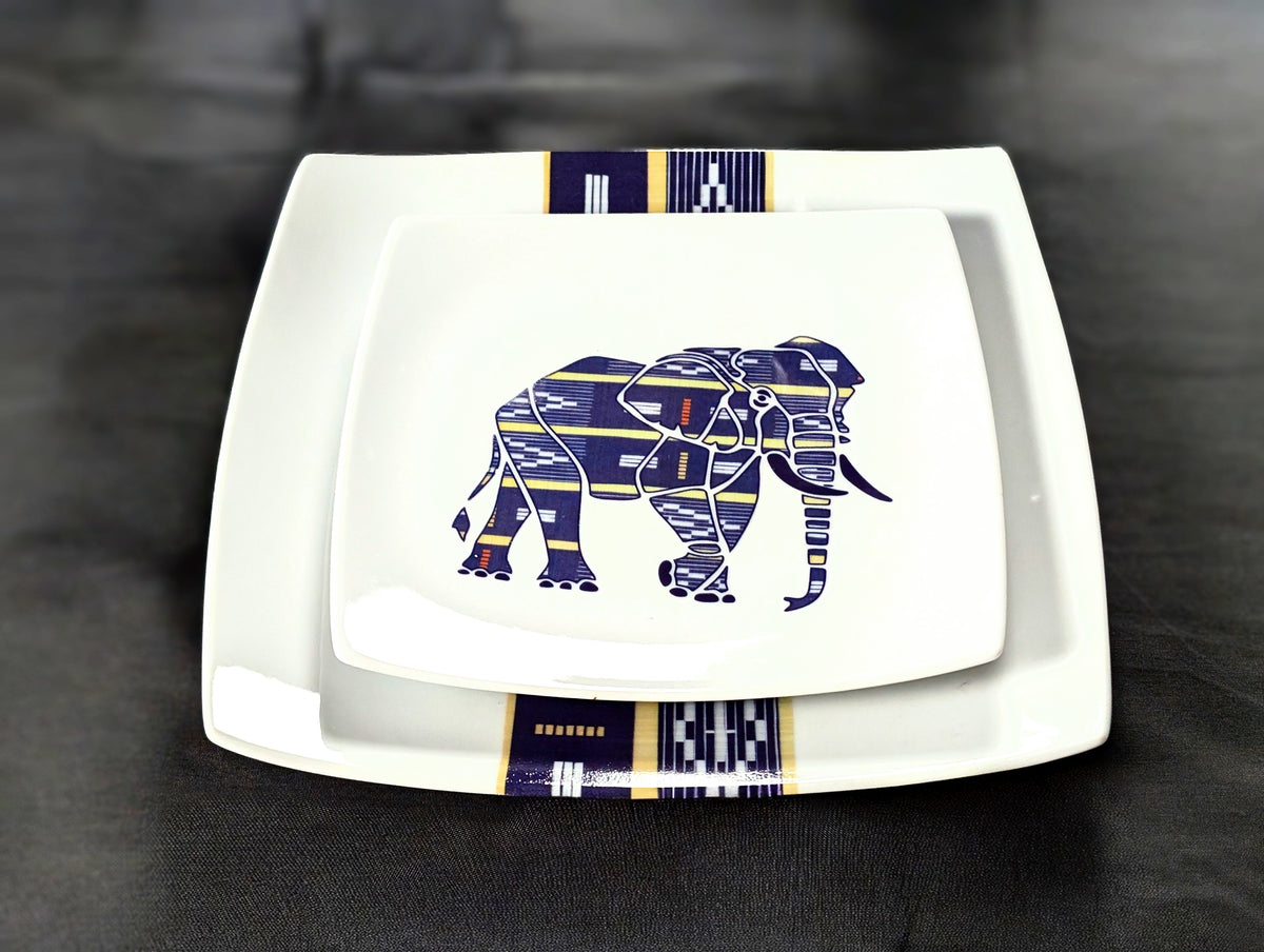 Plan rapproché frontal sur deux assiettes carrées Baoulé empilées, éléphant violet et bande tissée, fond gris