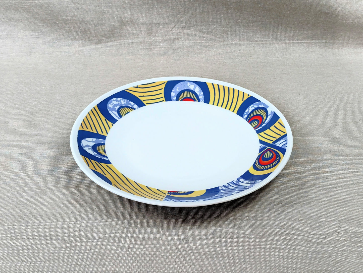 Coffret d'assiettes rondes en porcelaine fine Française fabriquées à la demande avec motif anneaux larges WAX d'afrique "Nos destins entrelacés" dans coffret de 6 assiettes.