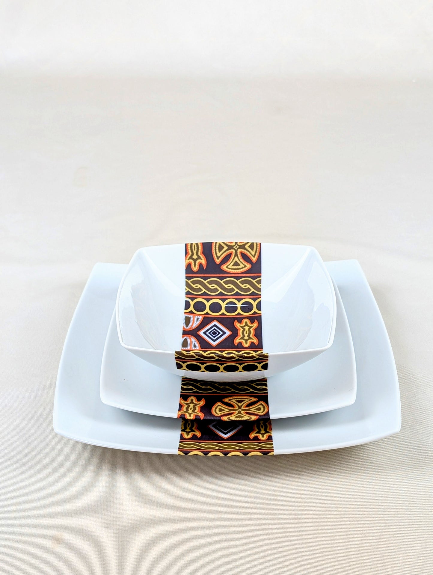 Coffret d'assiettes carrées en porcelaine fine Française fabriquées à la demande avec motif bande ethnique d'Afrique "Ndop" noir du Cameroun, présenté dans un coffret de 6 assiettes.